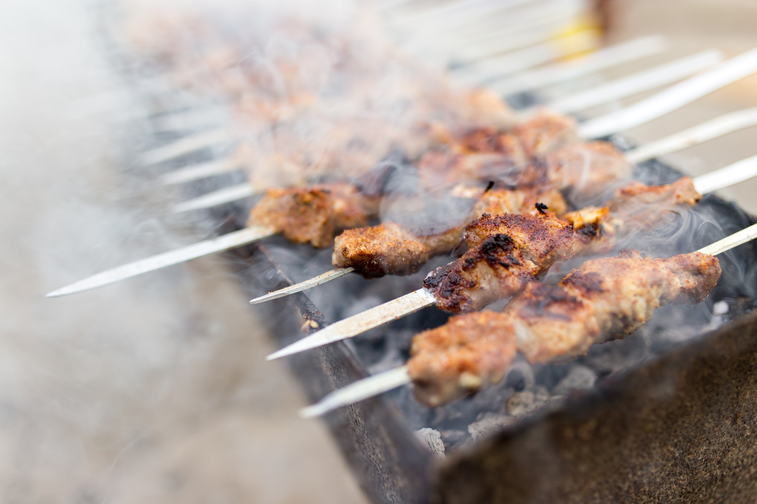 Grilled meat skewers cooking over charcoal